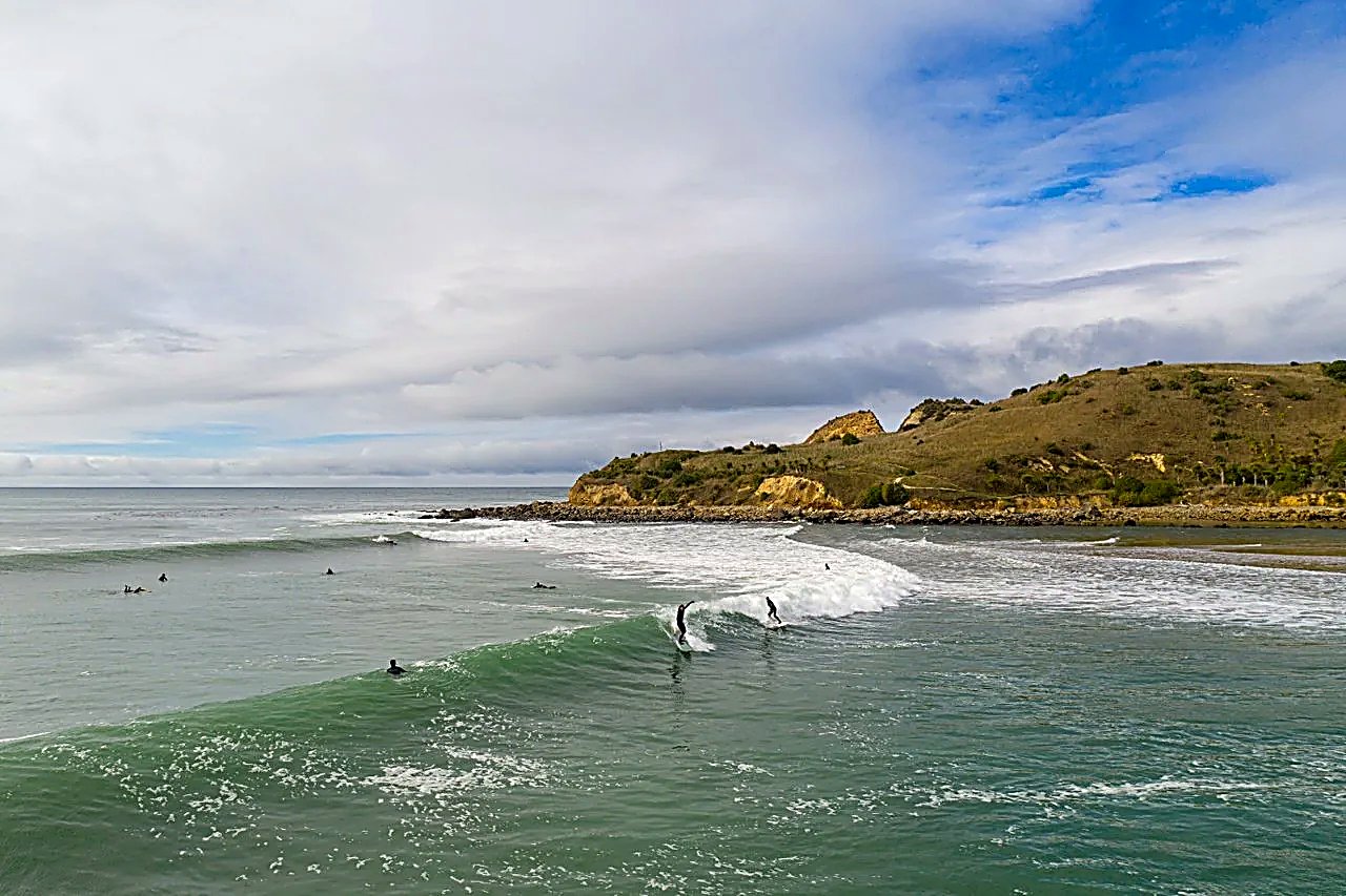A crew picking off the river-mouth bar as it reels along the sand, the yellow cliffs of the point behind, Karitane Beach surf