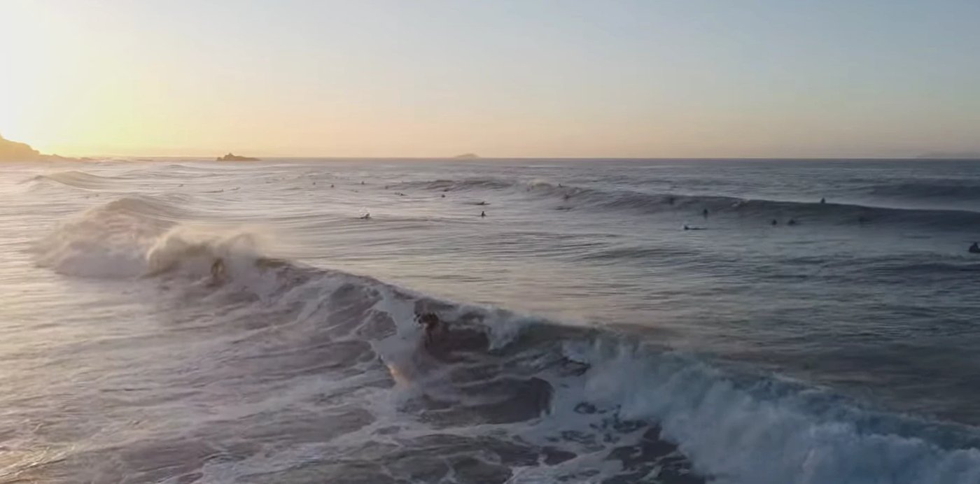 Sunset aerial of the Main Beach lineup with surfers spread across the bank, Mt Maunganui - Main Beach surf spot, Bay of Plent
