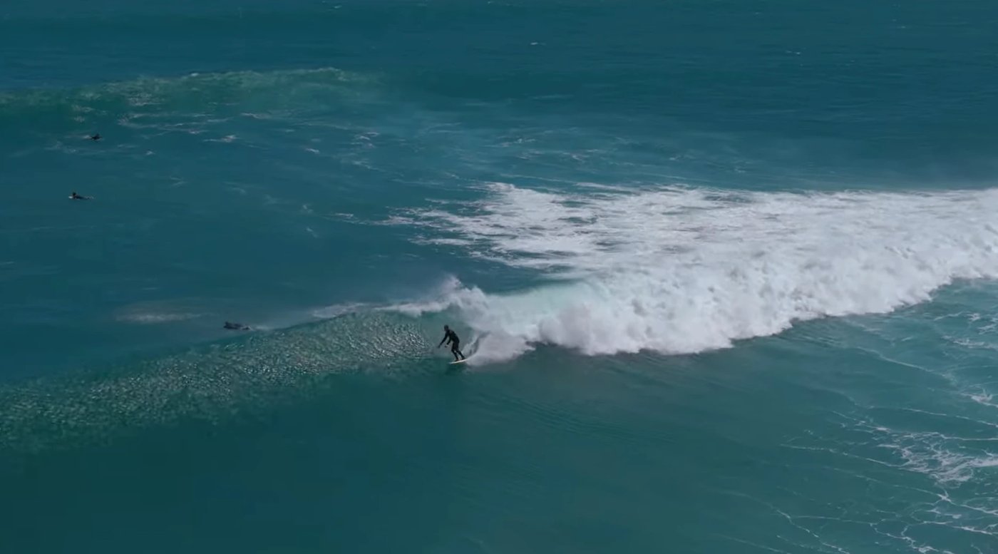 A surfer gliding a clean blue wall on the Taranaki coast at Opunake, Opunake surf spot, Taranaki / SH45, New Zealand.