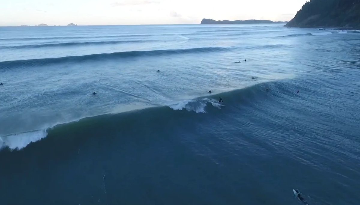 Dawn lineup with a few surfers and the Tairua harbour headland on the right. The morning crew before the holiday crowd arrive