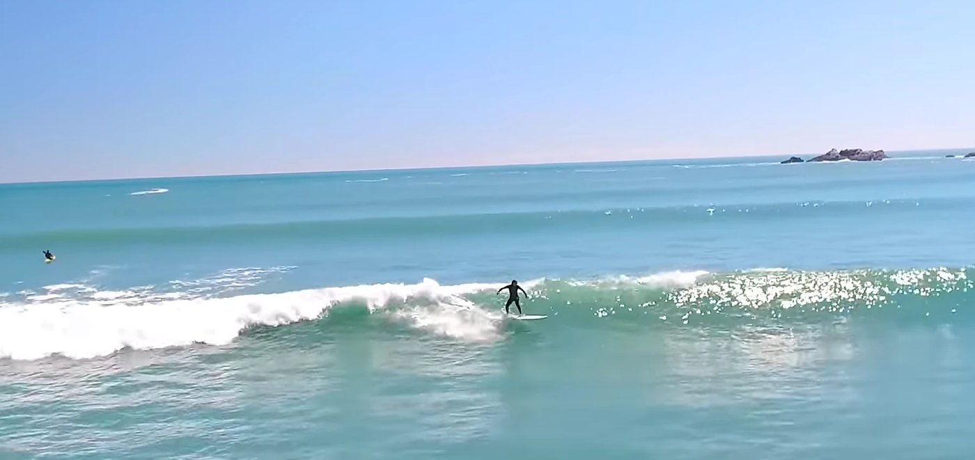A surfer trims along a clean little wall on a sun-drenched West Coast afternoon, Tauranga Bay surf spot, West Coast South Isl