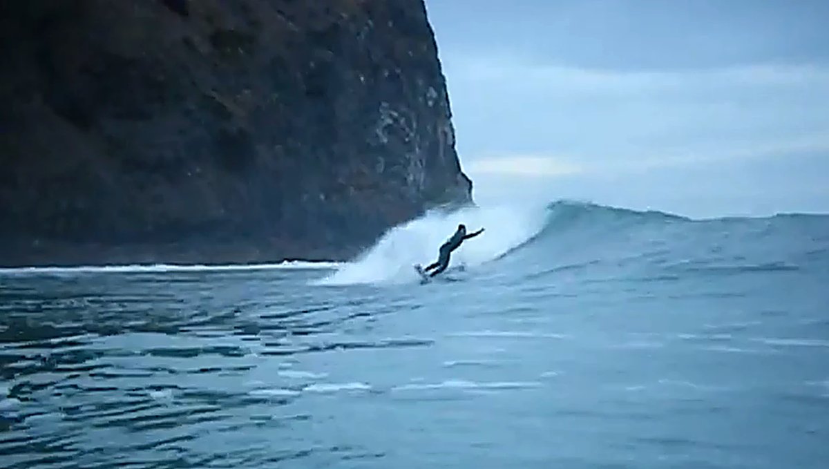 Dropping in under the dark headland as a clean peak swings through, Whangamoa surf spot, Marlborough / Nelson, New Zealand.